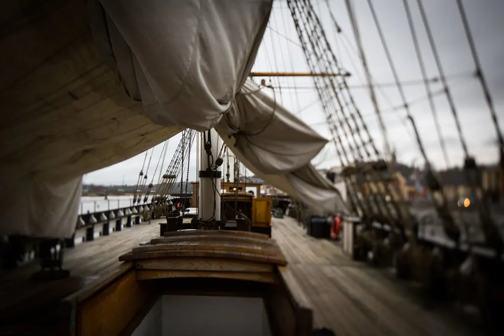 Deck view of a tall ship with billowed sails and rigging lines
