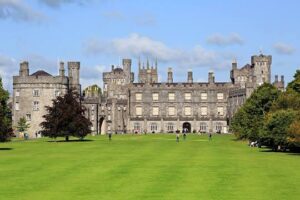 Stone castle with multiple turrets and manicured lawn in bright daylight