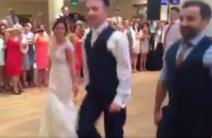 Bride and groom dancing at wedding reception with guests watching