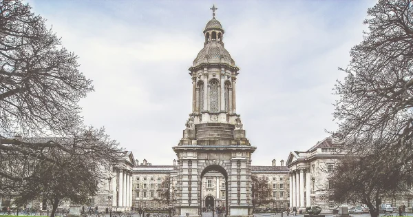 Historic stone building with dome and colonnade entrance, bare trees flanking