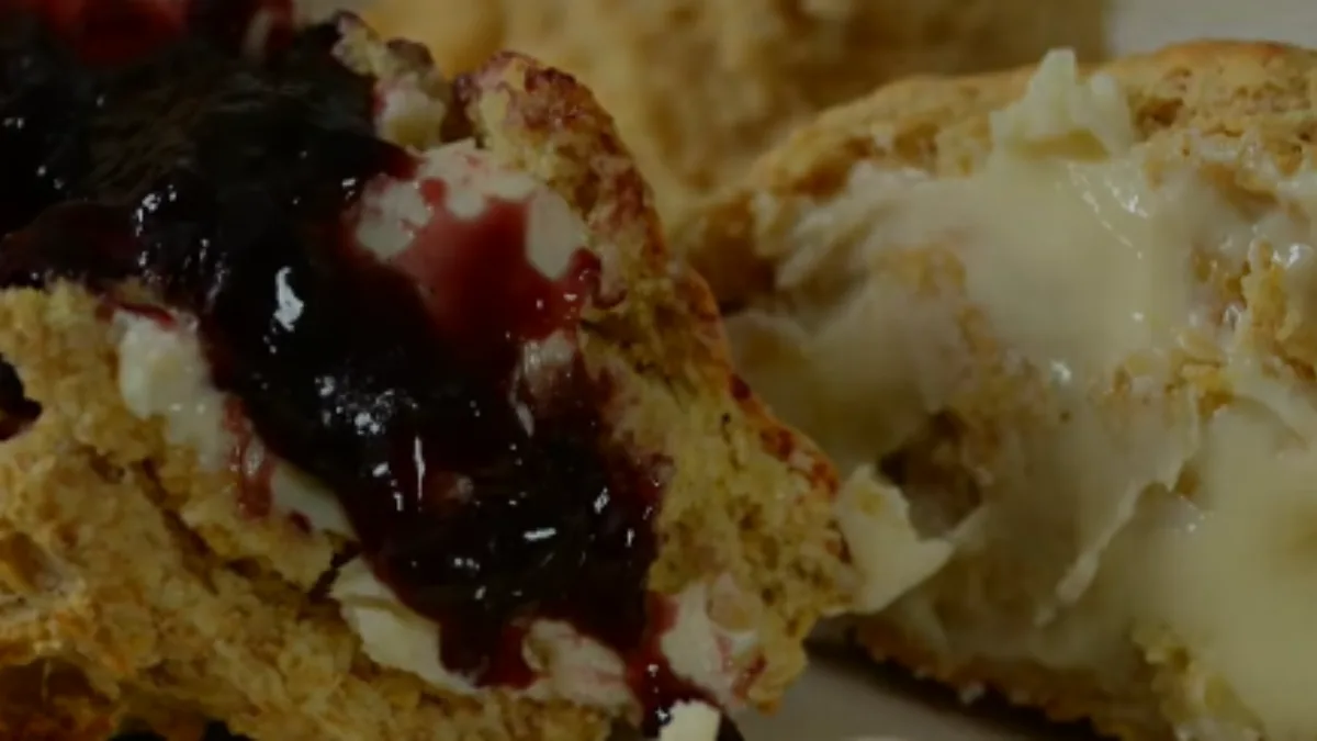 Sliced scones with clotted cream and dark red jam filling