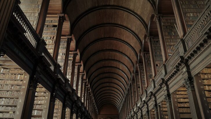 Long library corridor with arched wooden ceiling and floor-to-ceiling bookshelves
