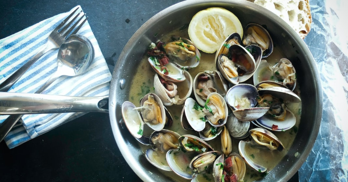 A pan of steamed clams with lemon and crusty bread, a generic seafood dish stock photo