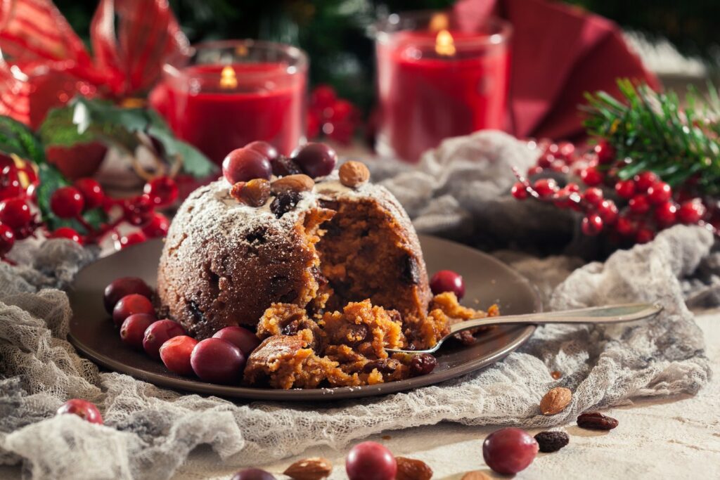 A Christmas pudding dusted with icing sugar, with cranberries and almonds