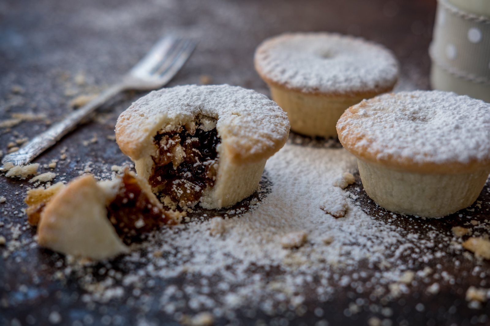 Mince pies dusted with icing sugar, one broken open