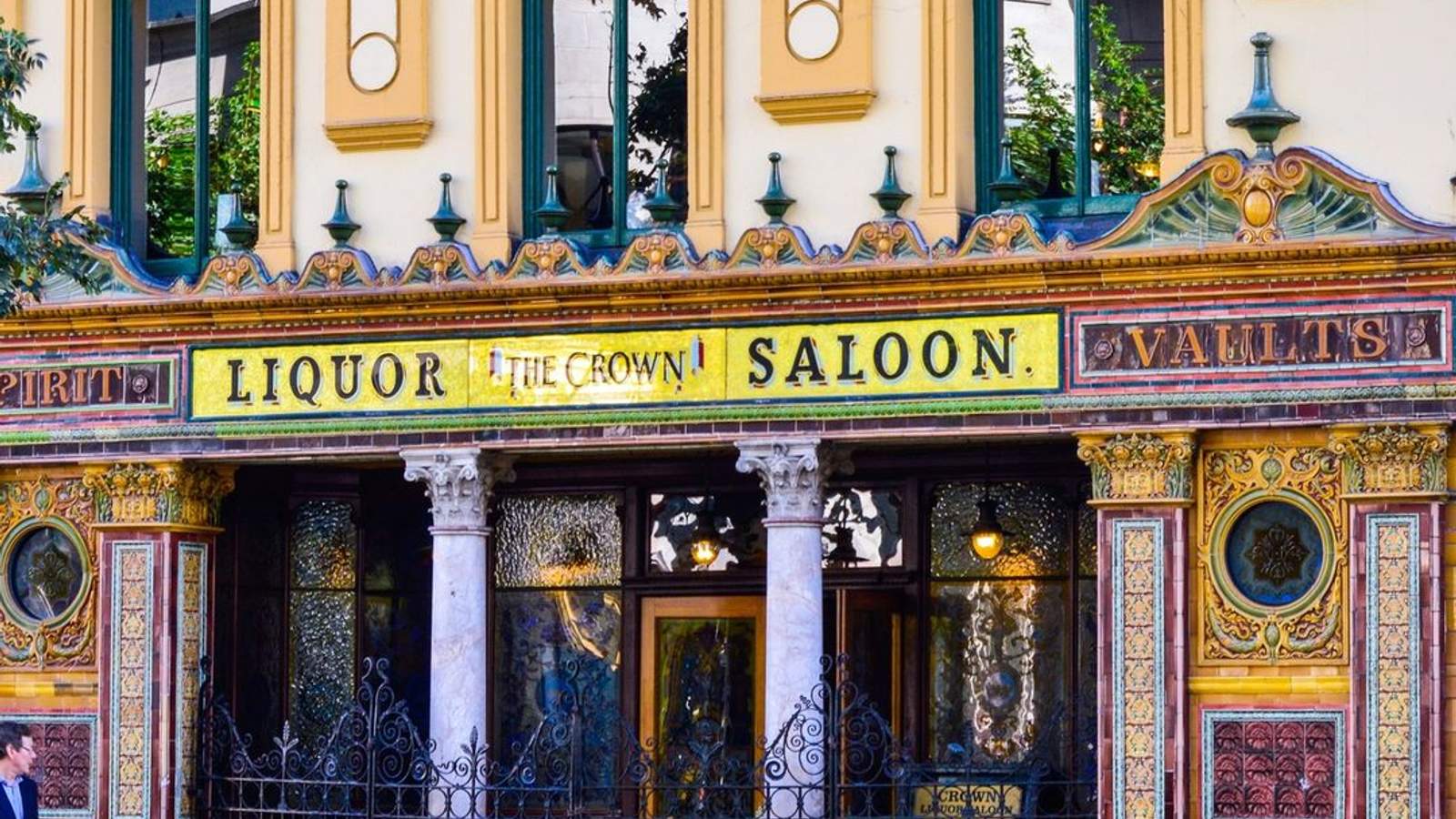 The ornate Victorian facade of The Crown Bar in Belfast, showing its elaborate tiled exterior and saloon signs