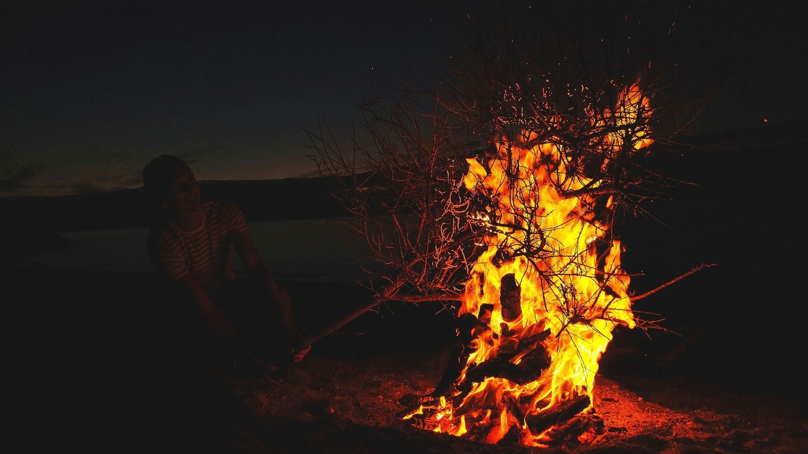 People gathered around a blazing bonfire on an Irish beach at night for St John's Night celebrations