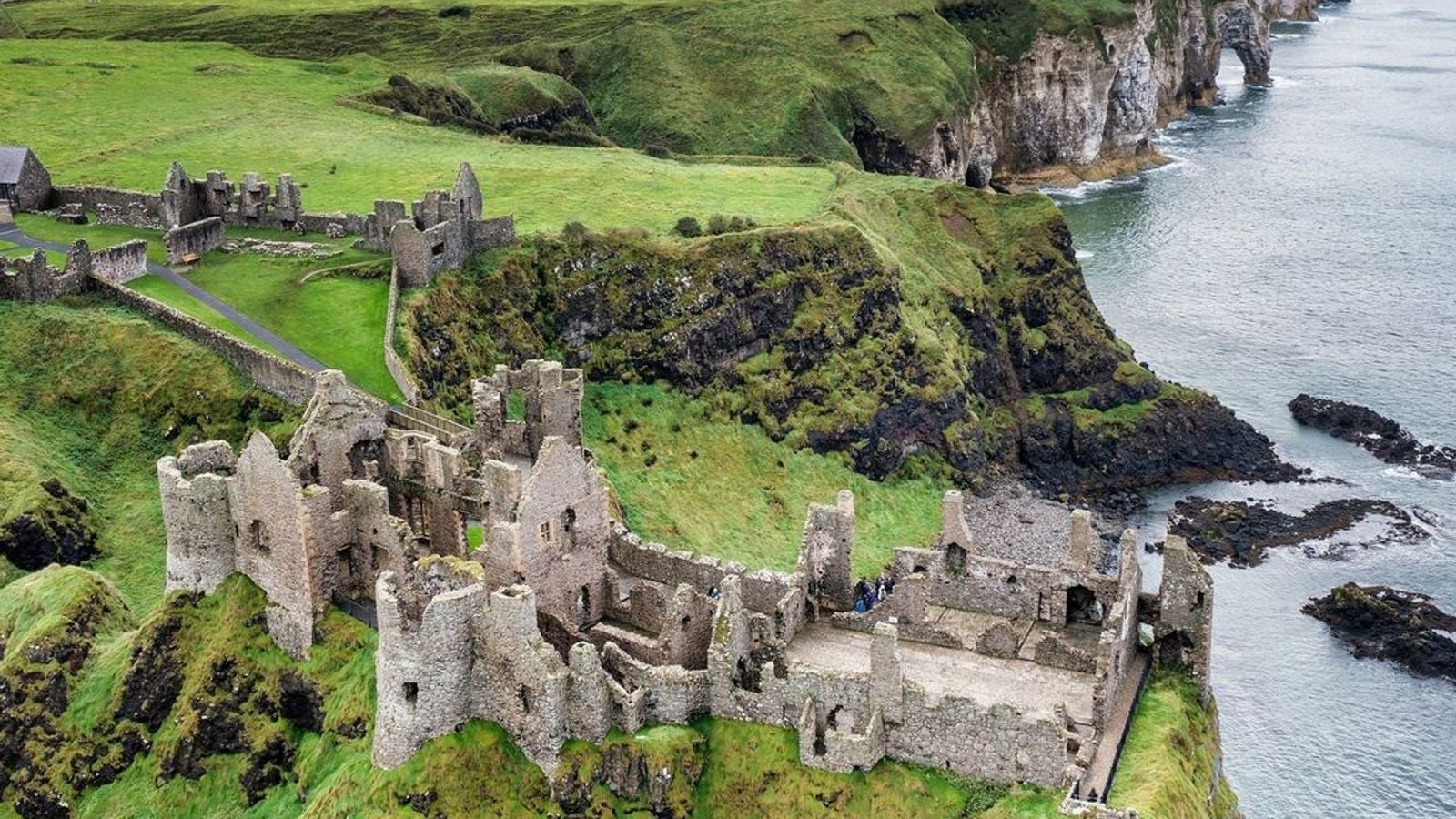 Aerial view of Dunluce Castle perched dramatically on the Antrim coast cliffs above the sea
