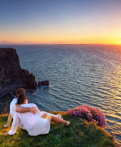 Couple watching sunset over the Cliffs of Moher, Ireland