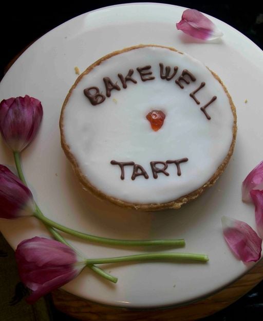 Classic Bakewell Tart with raspberry jam, almond frangipane, flaked almonds and white icing drizzle