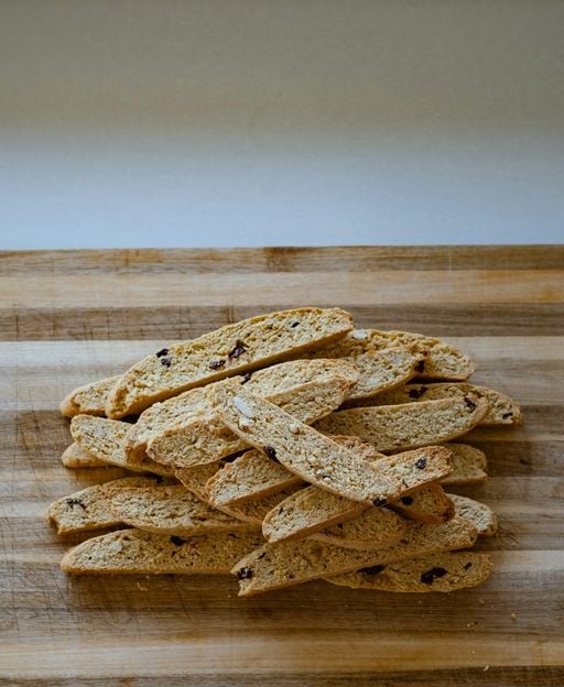 Golden-brown cantucci biscotti with almonds and cranberries on a wooden cutting board