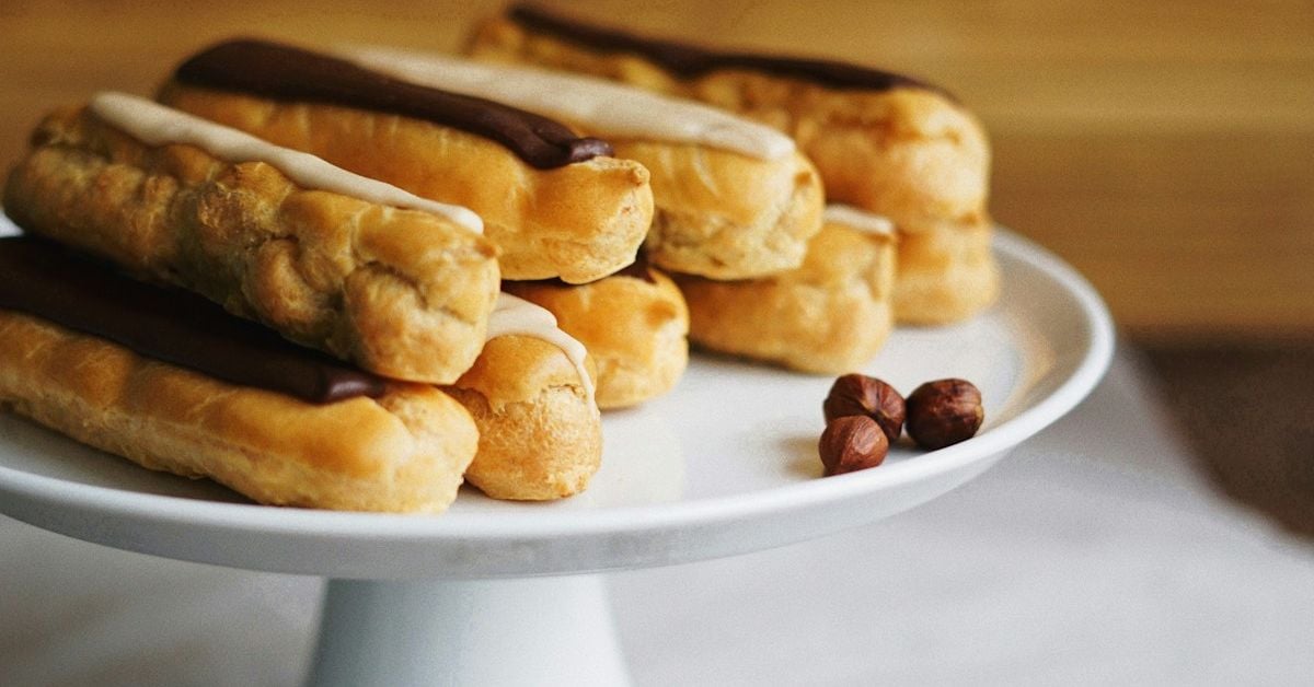 A tray of freshly baked chocolate eclairs with glossy dark chocolate glaze