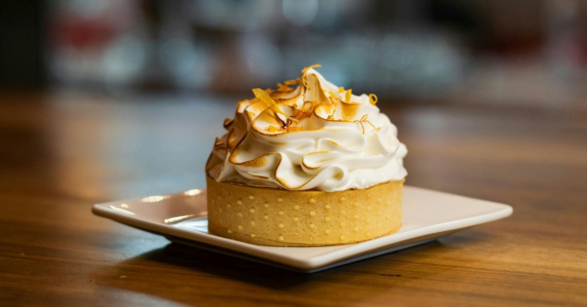 Classic lemon tart with golden pastry case and smooth lemon curd filling on a white plate