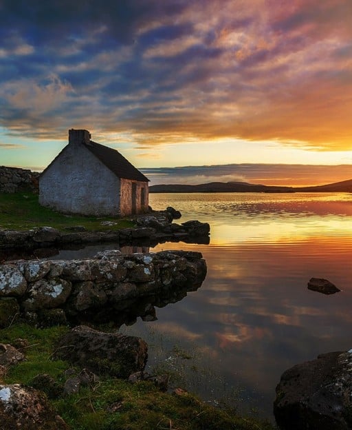 Sunset over a cottage by a lough in Connemara, Ireland