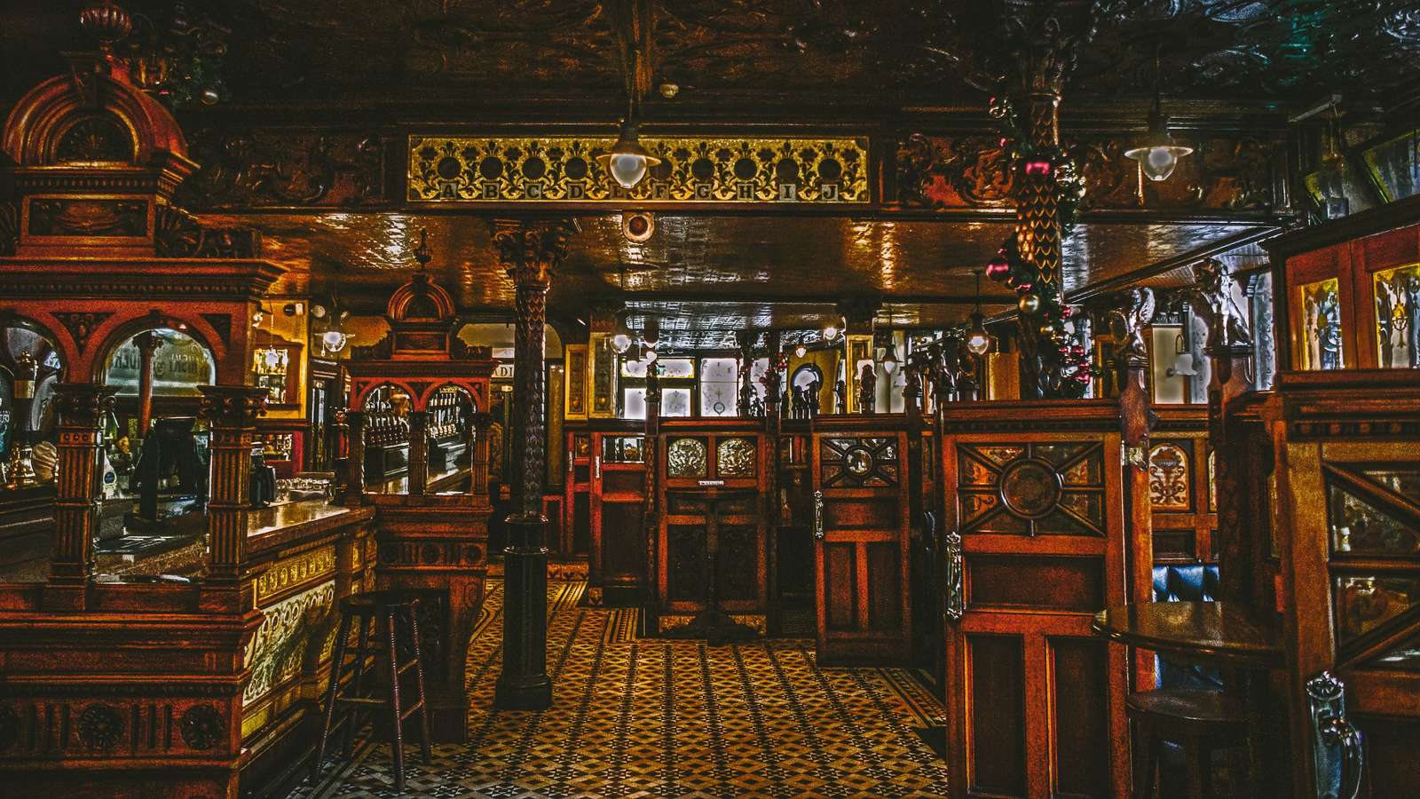 The ornate Victorian interior of a historic Irish pub with carved wooden booths and mosaic floor