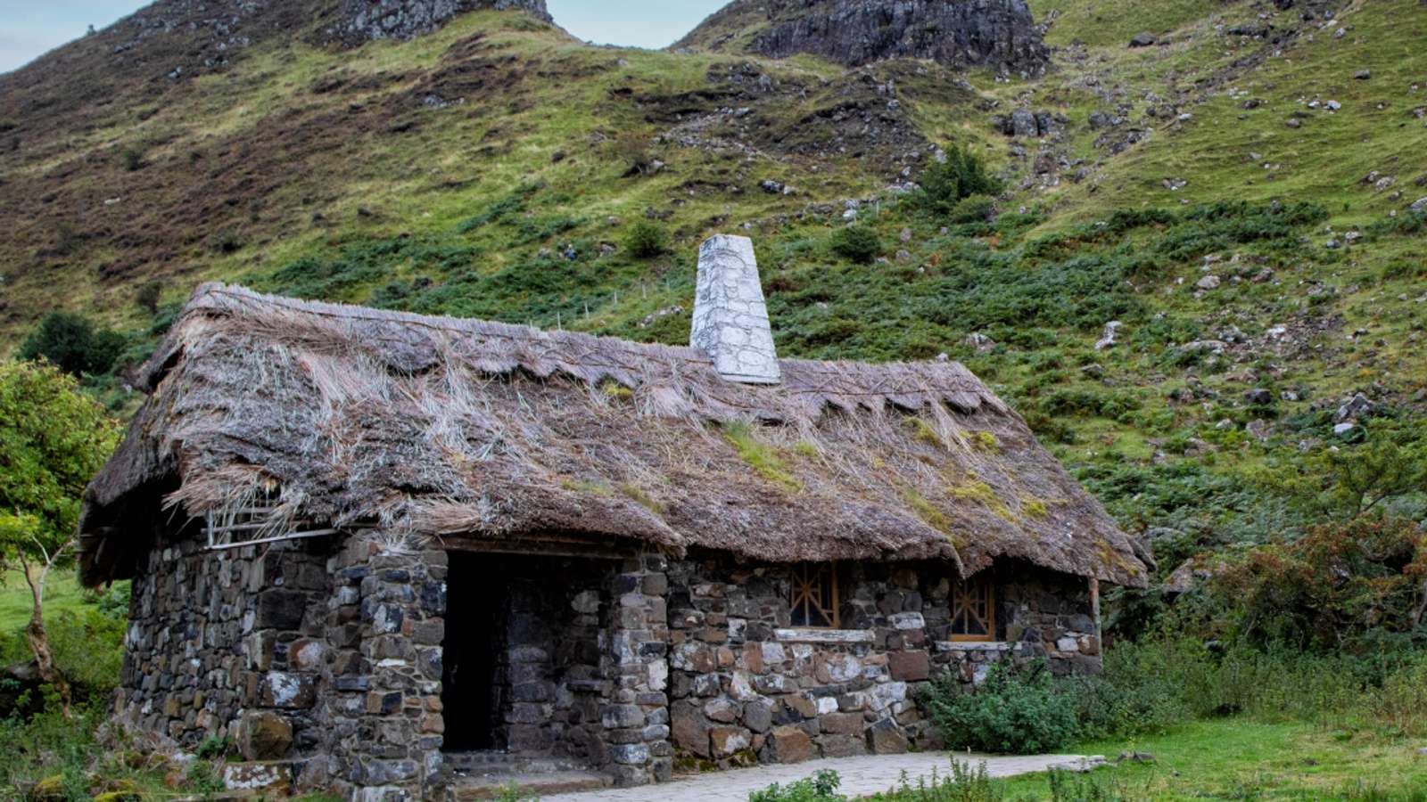 Remote stone cottage ruins in a dramatic Irish mountain valley with rocky peaks