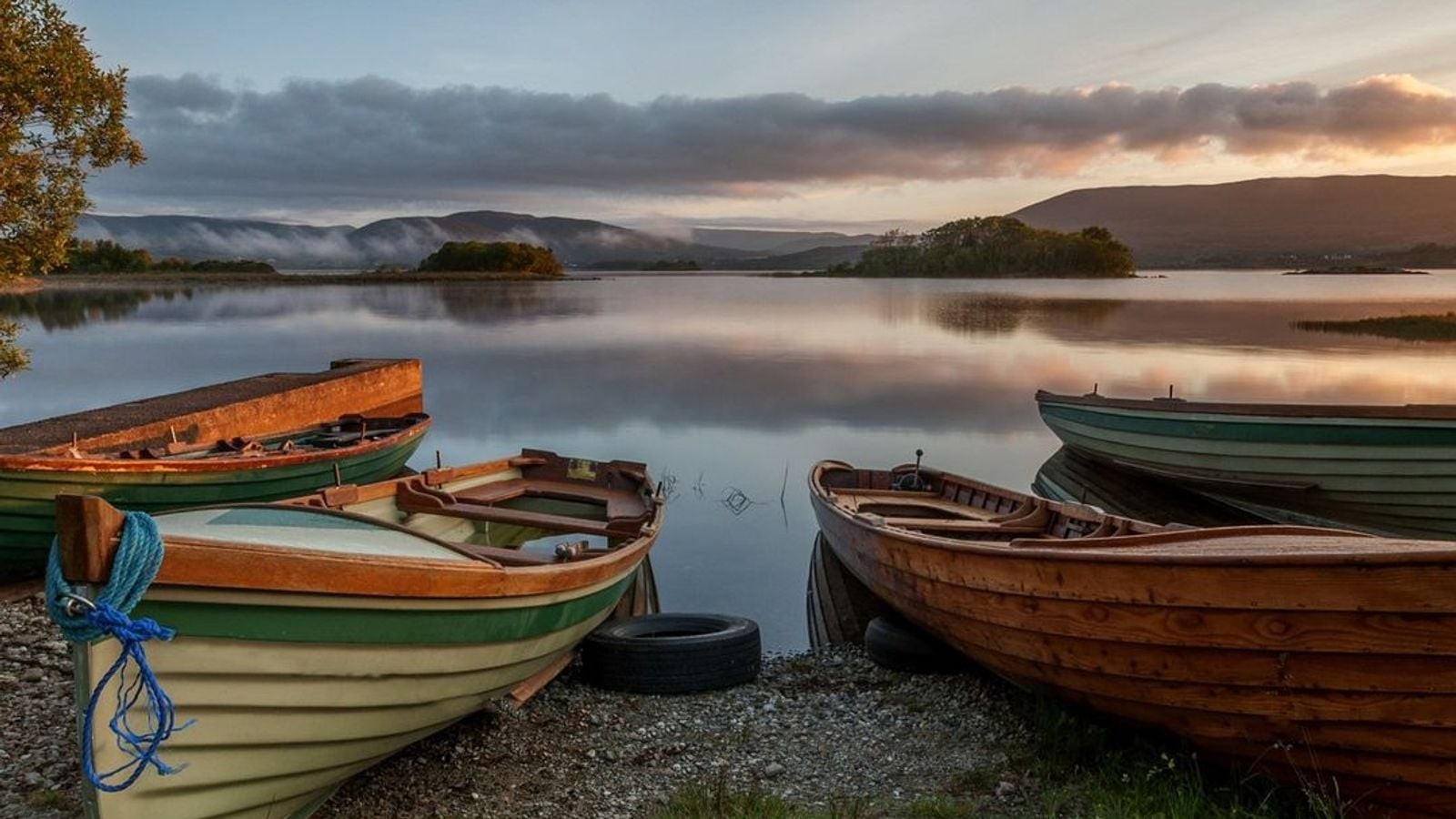 Traditional wooden rowing boats resting on the shores of Lough Corrib in Connemara, Ireland, at dawn