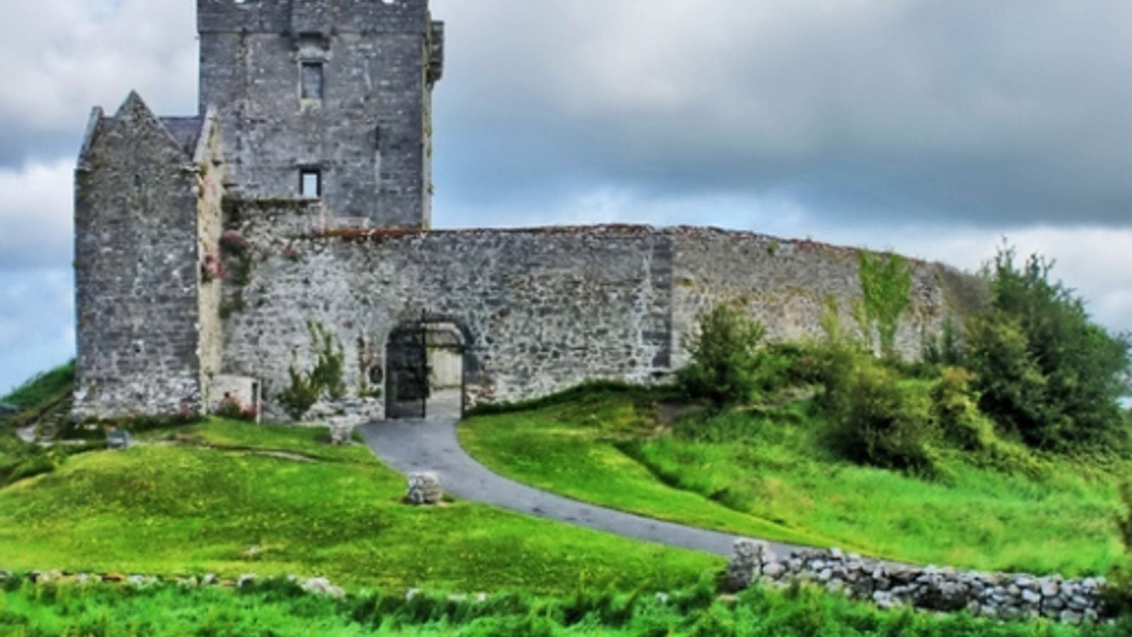 A 16th-century Irish tower house standing on a green hillside overlooking Galway Bay
