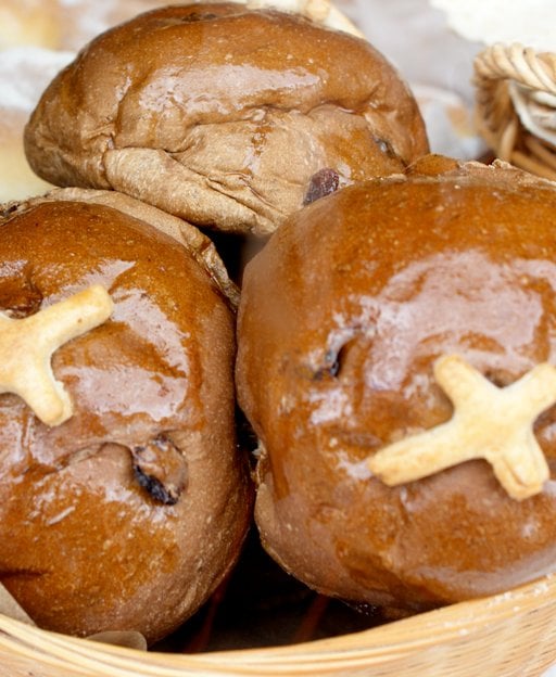 Freshly baked hot cross buns with glossy glaze and white crosses, arranged in a basket - traditional Irish Easter baking