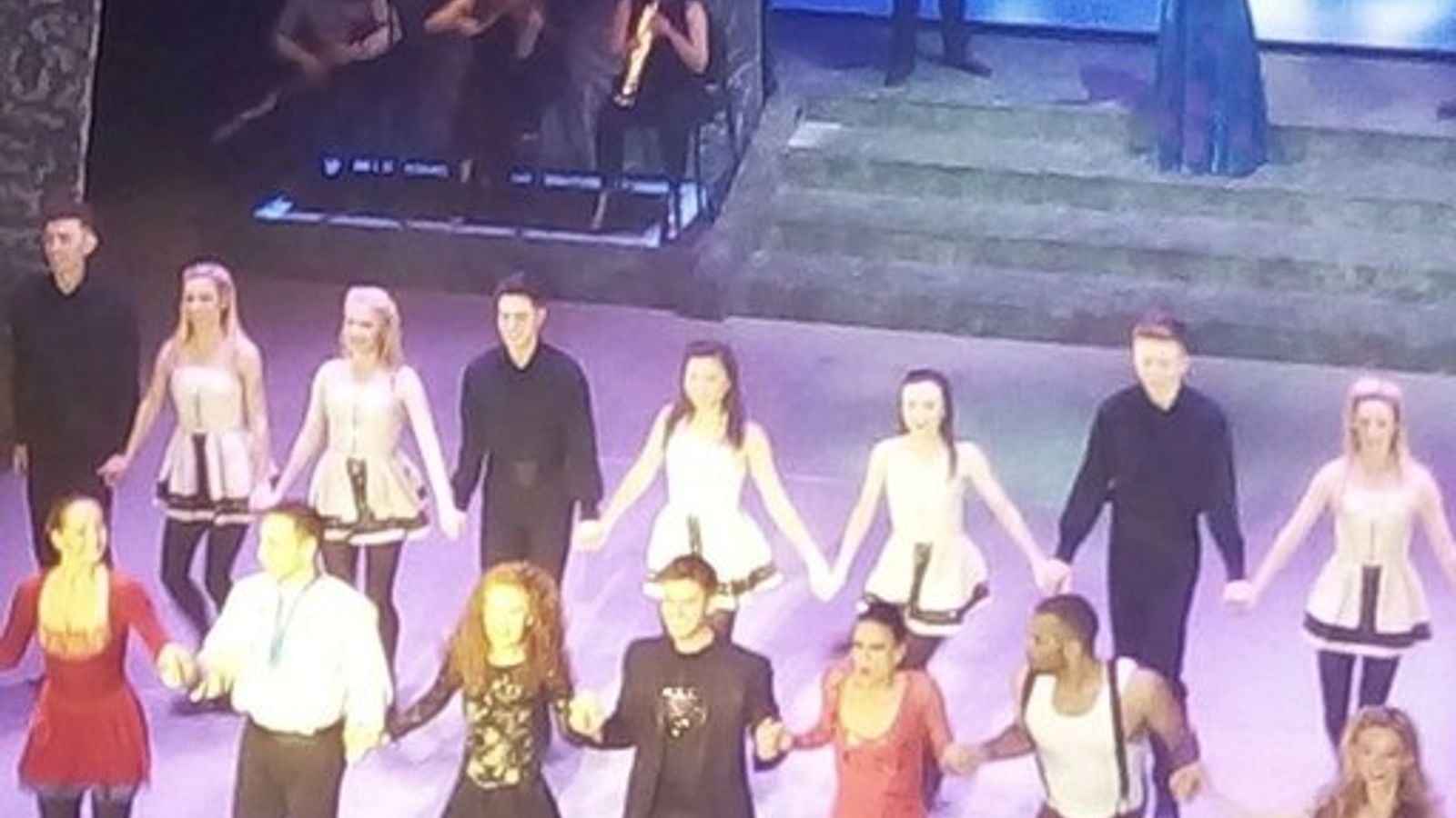 Irish step dancers performing on stage in elaborate embroidered costumes