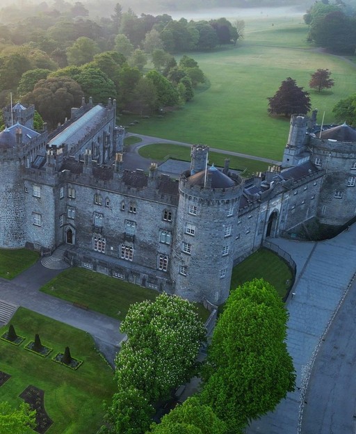 Aerial view of a stone castle with manicured grounds and surrounding countryside