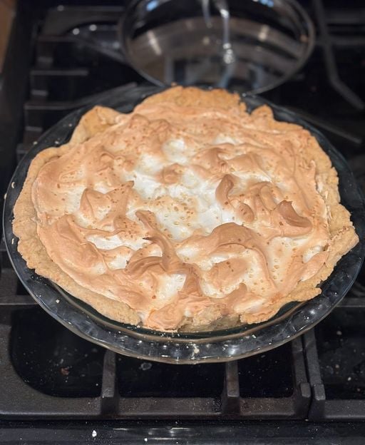 A slice of classic lemon meringue pie showing bright yellow lemon curd filling and fluffy meringue topping in a crisp pastry crust
