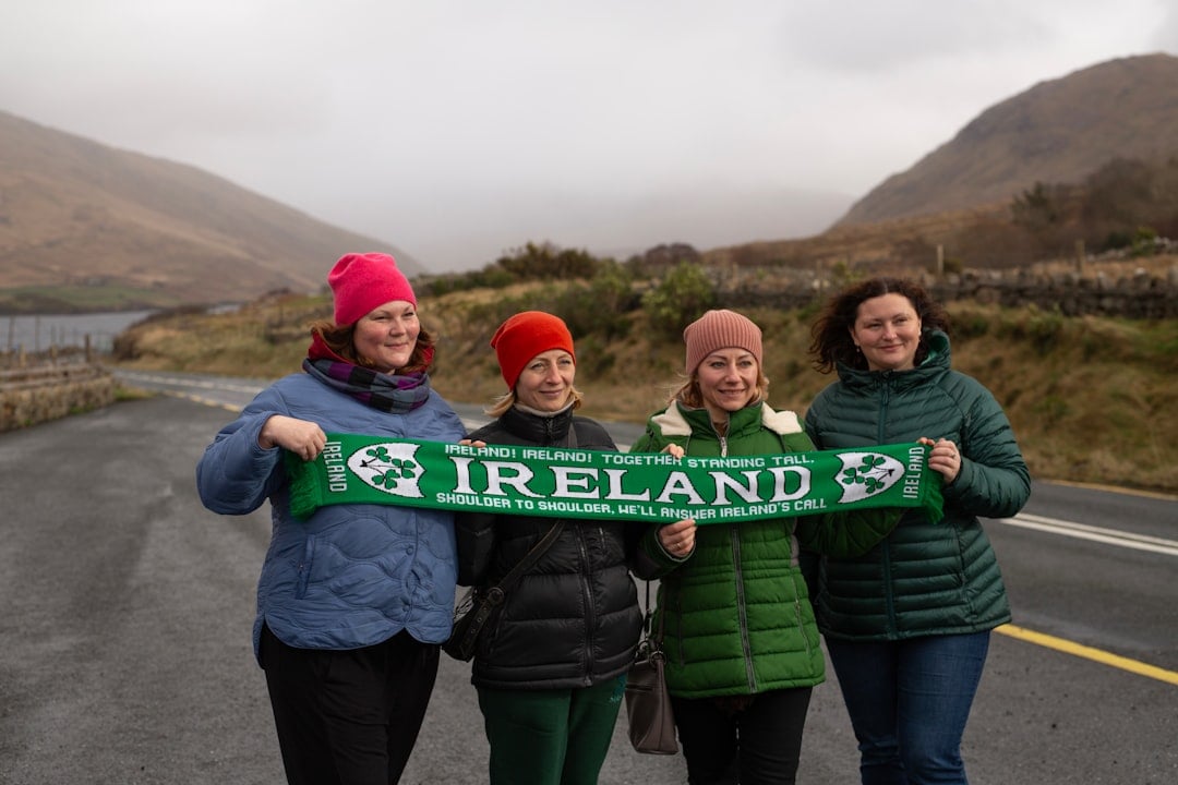 Four women hold an ireland scarf outdoors.