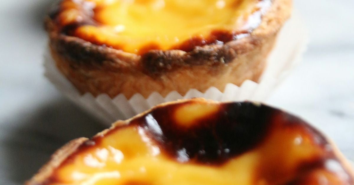 Three golden past&eacute;is de nata (Portuguese custard tarts) with flaky pastry and caramelised egg custard filling