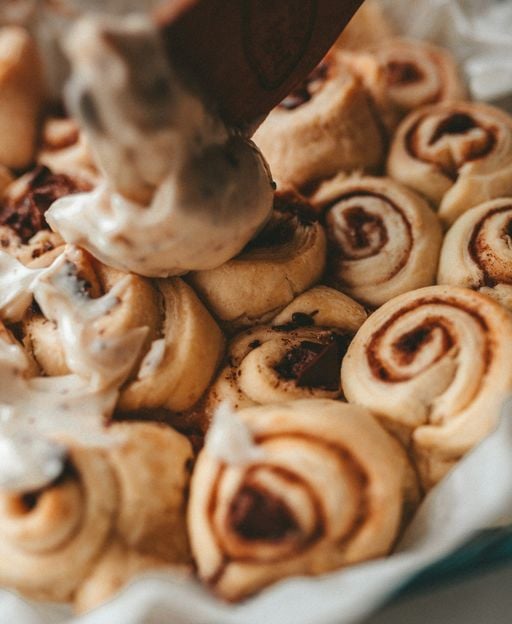 Small batch cinnamon rolls with cream cheese frosting in a parchment-lined baking dish