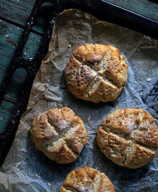 Freshly baked Irish soda bread rolls on a baking tray, showing characteristic cross cuts