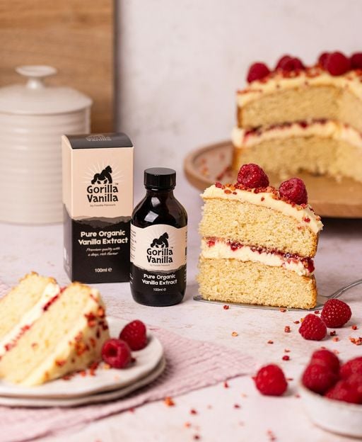 Slices of a golden vanilla sponge cake with raspberry jam, fresh cream and raspberries on top