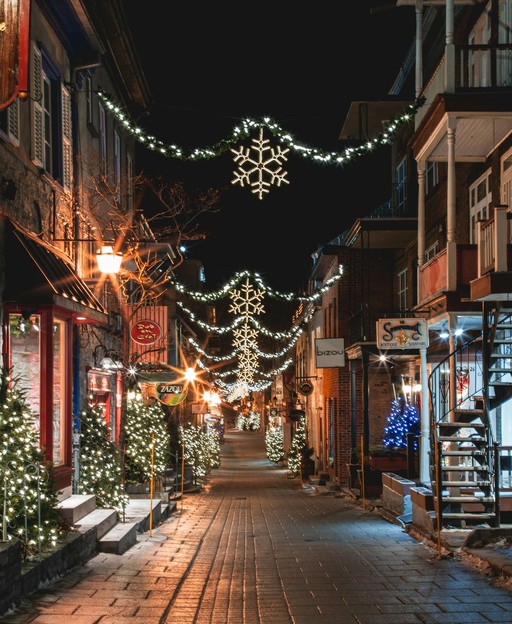 Festive city street decorated with Christmas lights and snowflake decorations at night
