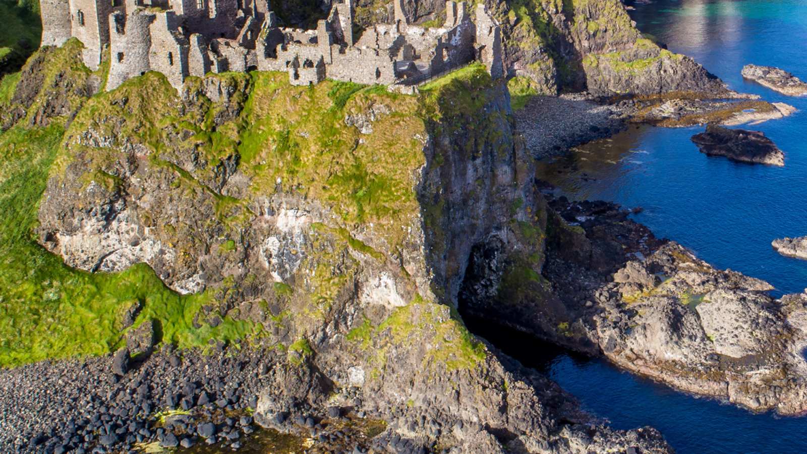 Aerial view of Dunluce Castle perched on dramatic coastal cliffs in County Antrim, Ireland
