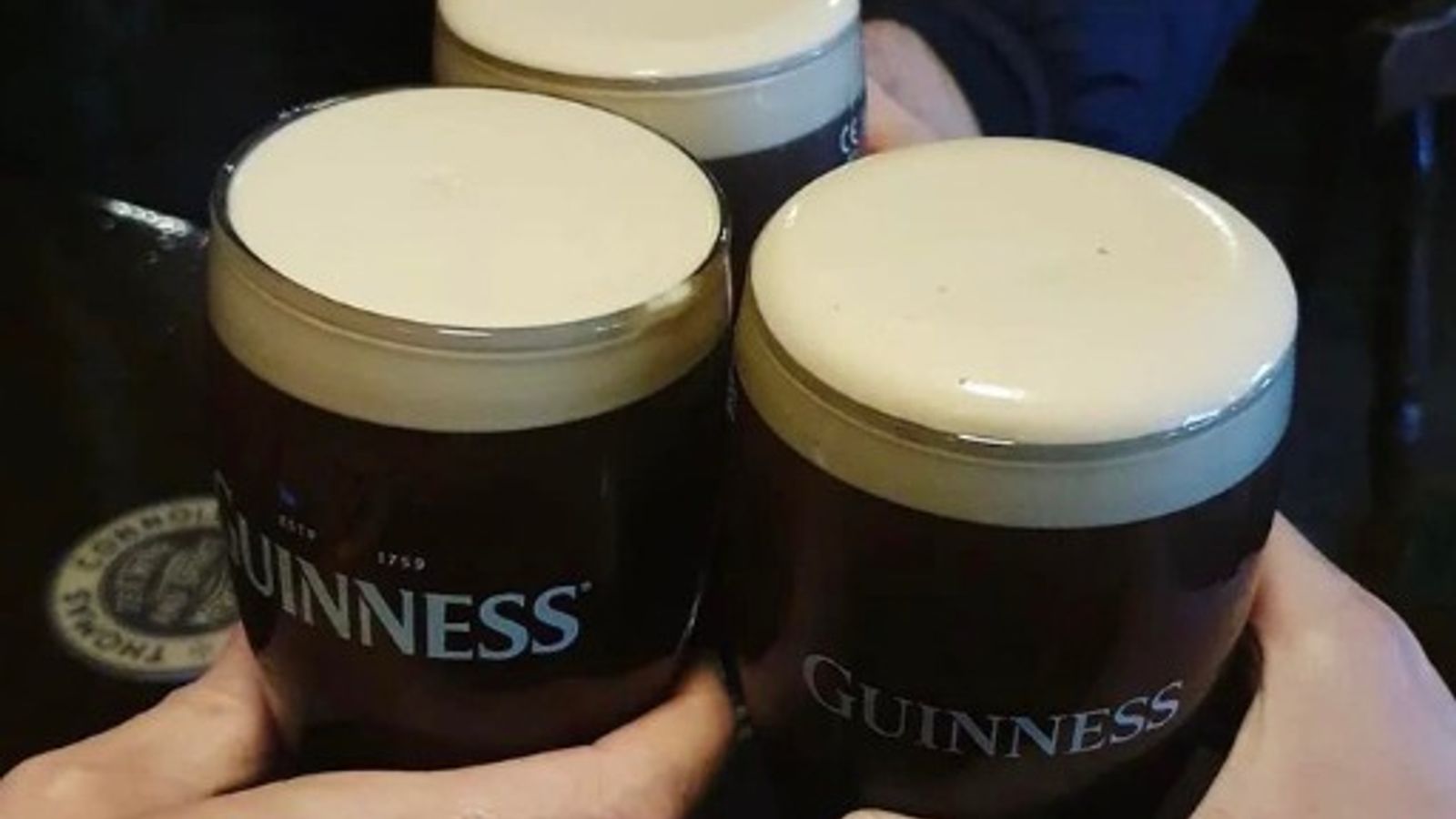 Three Guinness pints being toasted together in a dark Irish pub