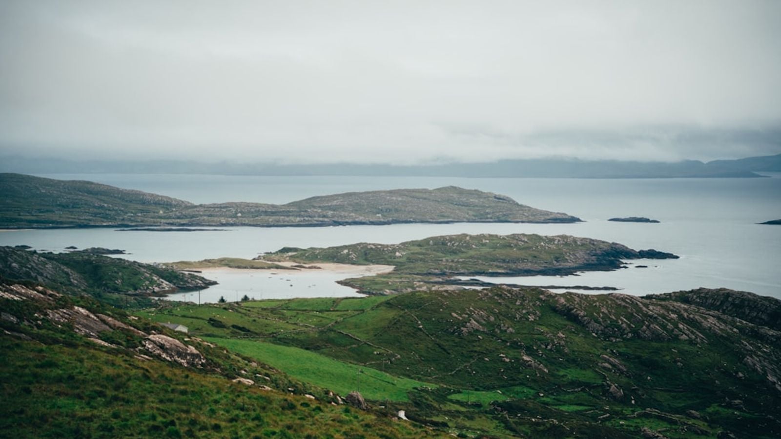 Rugged coastal islands with green fields and sandy beach off the Connemara coast, County Galway, Ireland