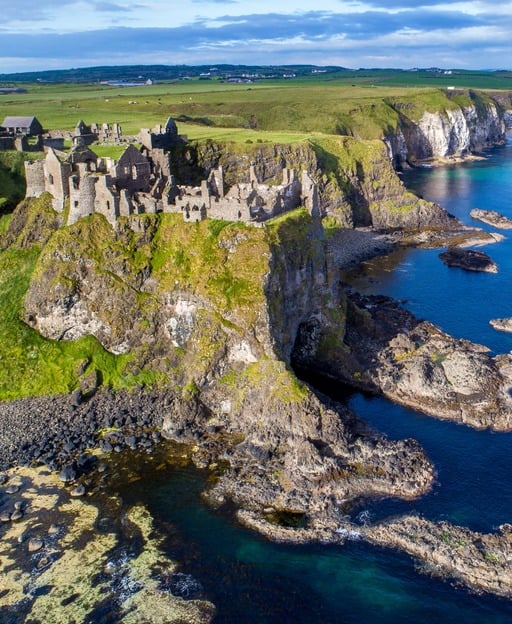 Aerial view of Dunluce Castle on the North Antrim coast, perched on a basalt cliff above the sea in County Antrim, Northern Ireland