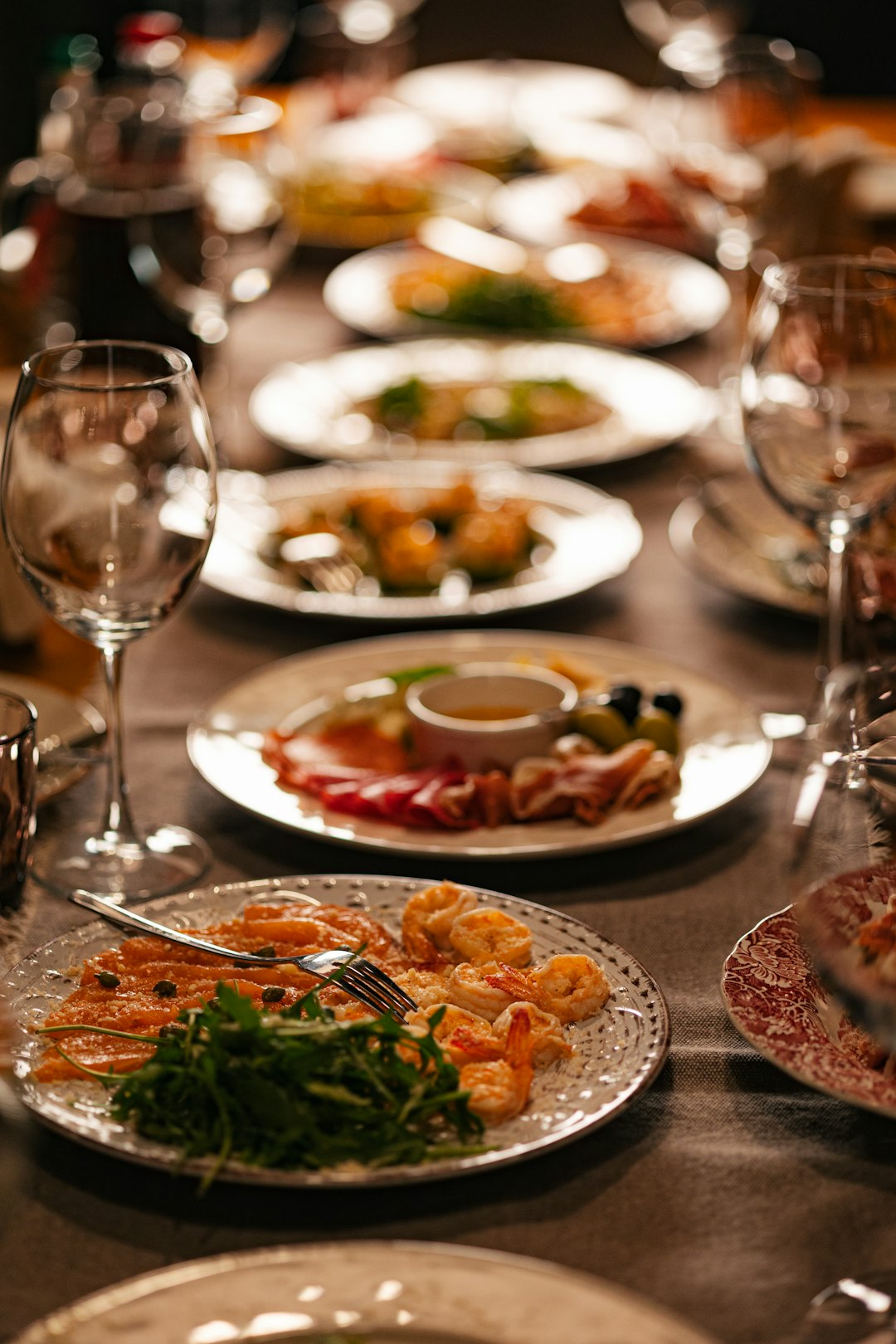 Fine dining table set with plated seafood course and wine glasses