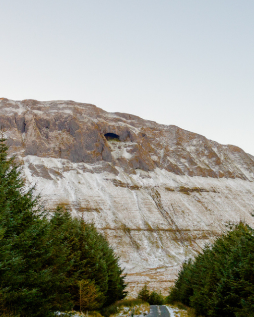 Gleniff Horseshoe Drive, County Sligo — limestone cliff face with cave opening, evergreen conifers and road below