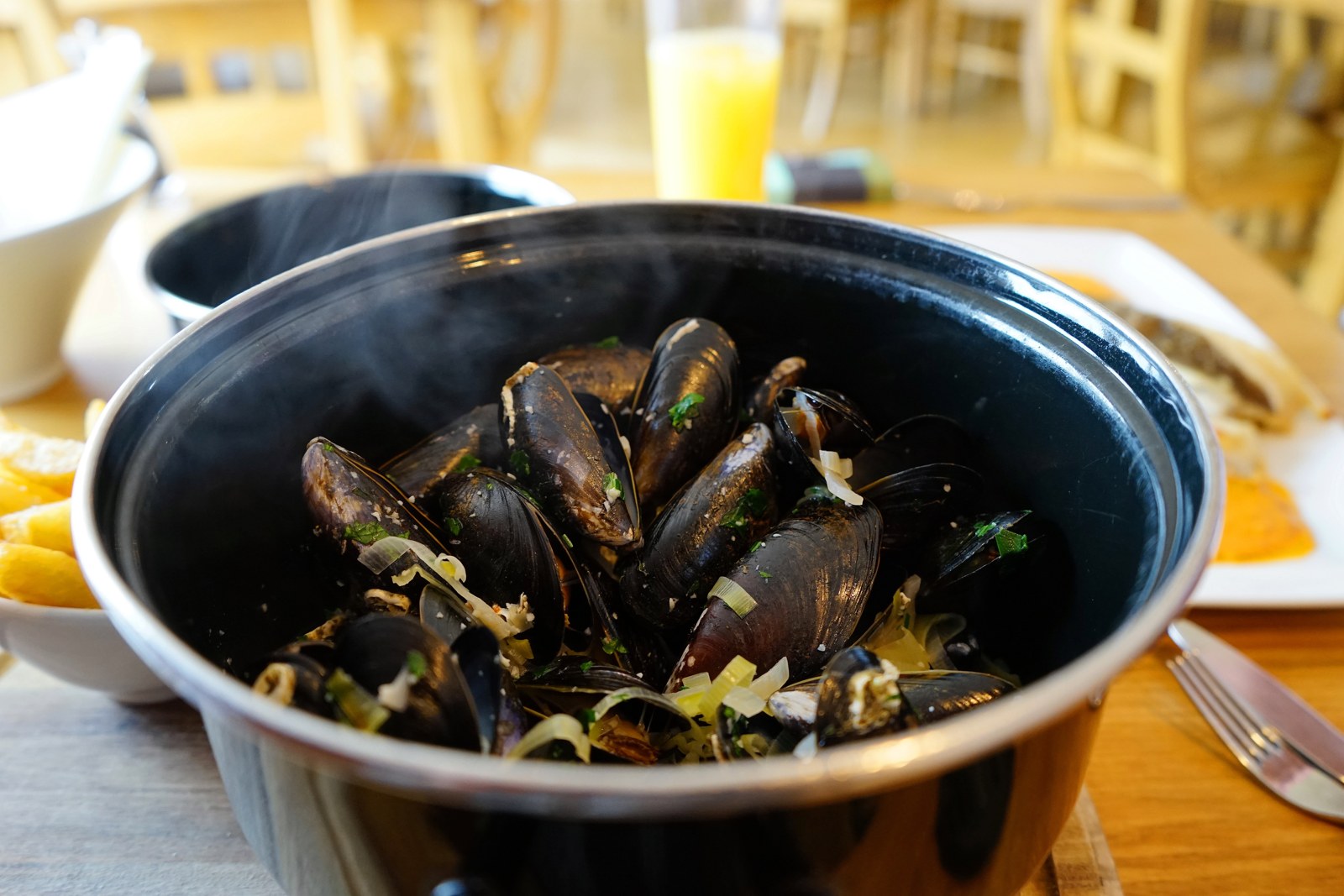 A bowl of cooked mussels in mariniere-style cream and white wine sauce, garnished with parsley
