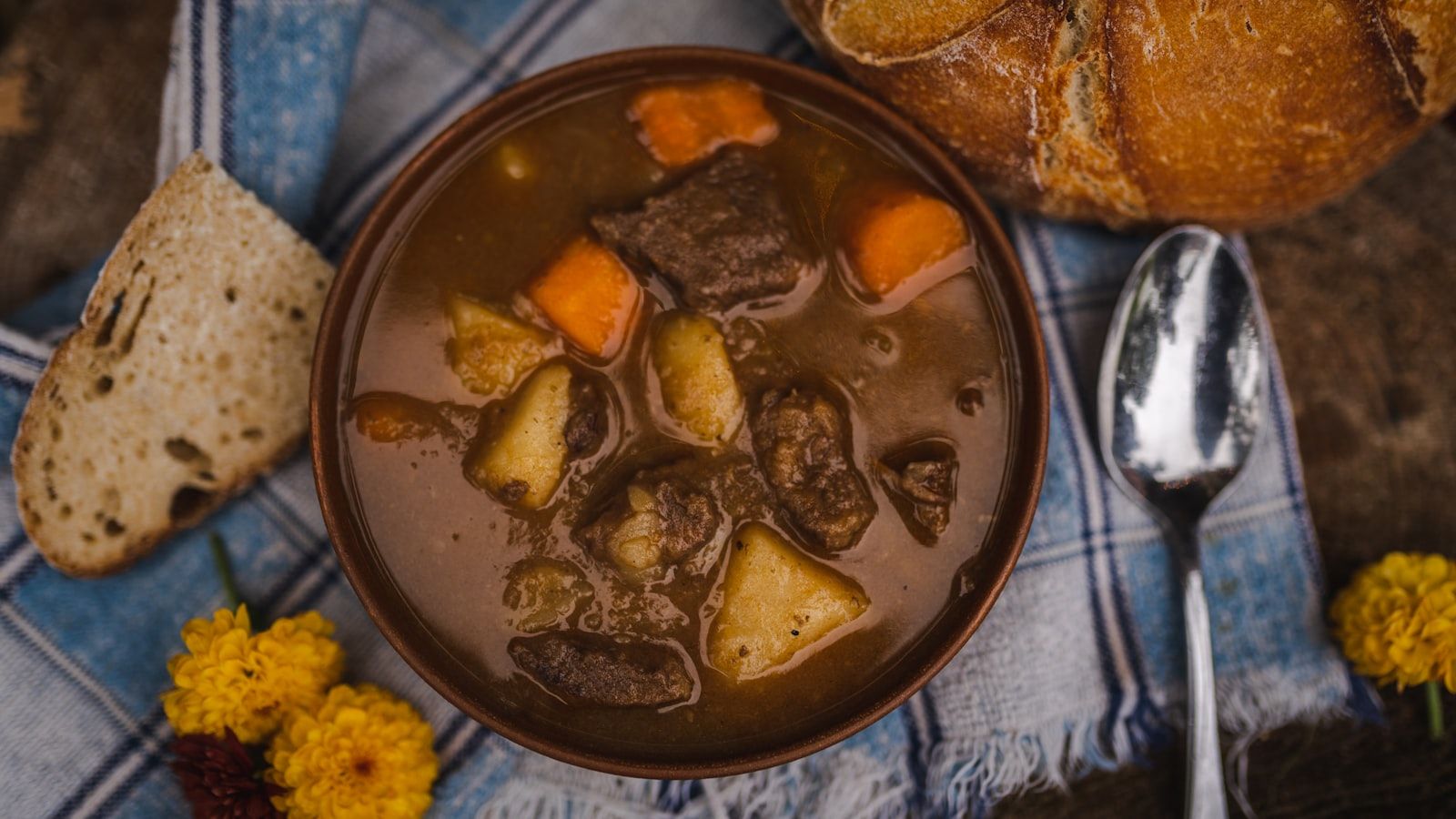 A rustic bowl of traditional Irish stew with chunks of beef, potato and carrot served with sourdough bread