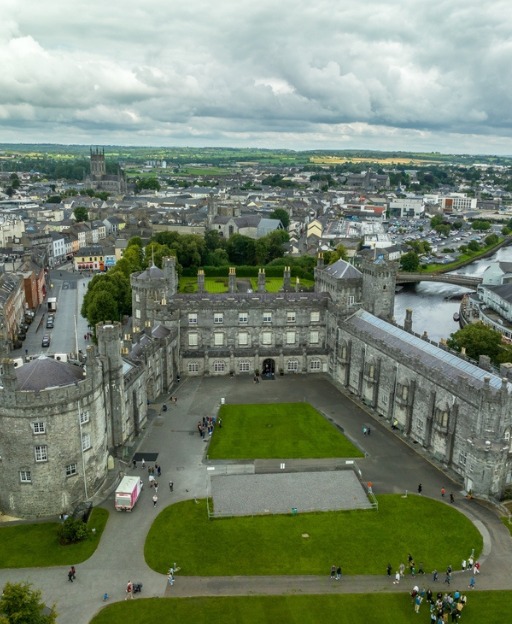 Aerial view of Kilkenny Castle and surrounding town with green lawns and buildings