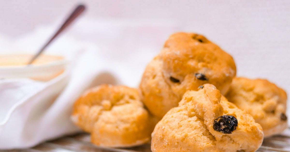 Golden-brown Irish raisin scones with visible currants, served with clotted cream and jam
