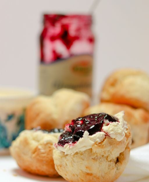 Golden treacle scones split open and served with cream and jam, freshly baked following a traditional Irish recipe