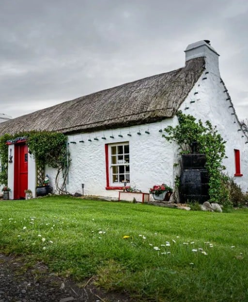 White thatched cottage with red door in rural Ireland