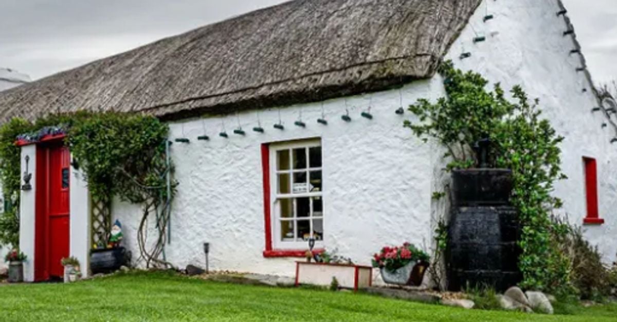 Traditional Irish thatched cottage with white walls and red door, rural Ireland