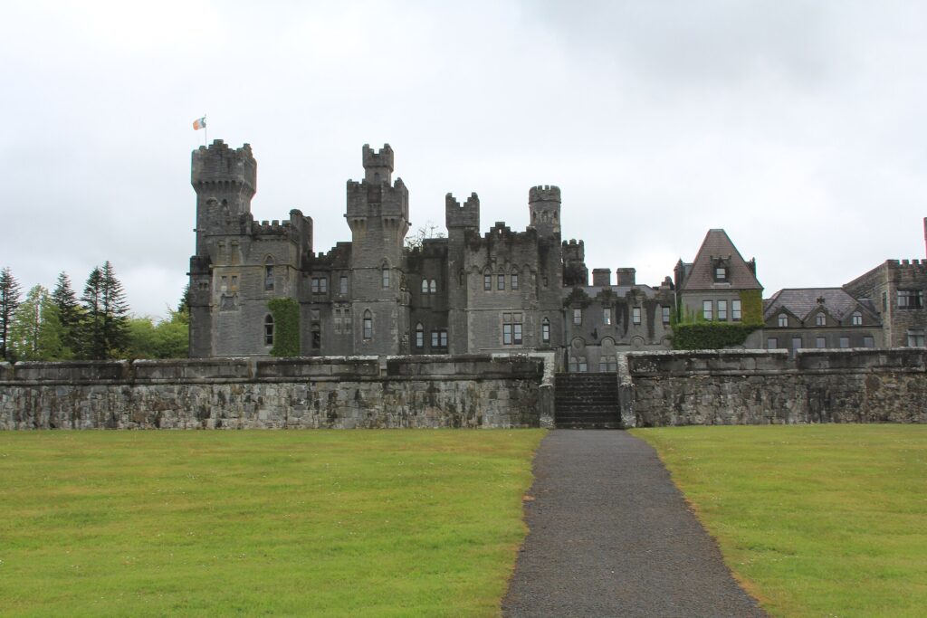 Ashford Castle's grey stone facade and turreted towers viewed across the front lawn, Cong, County Mayo