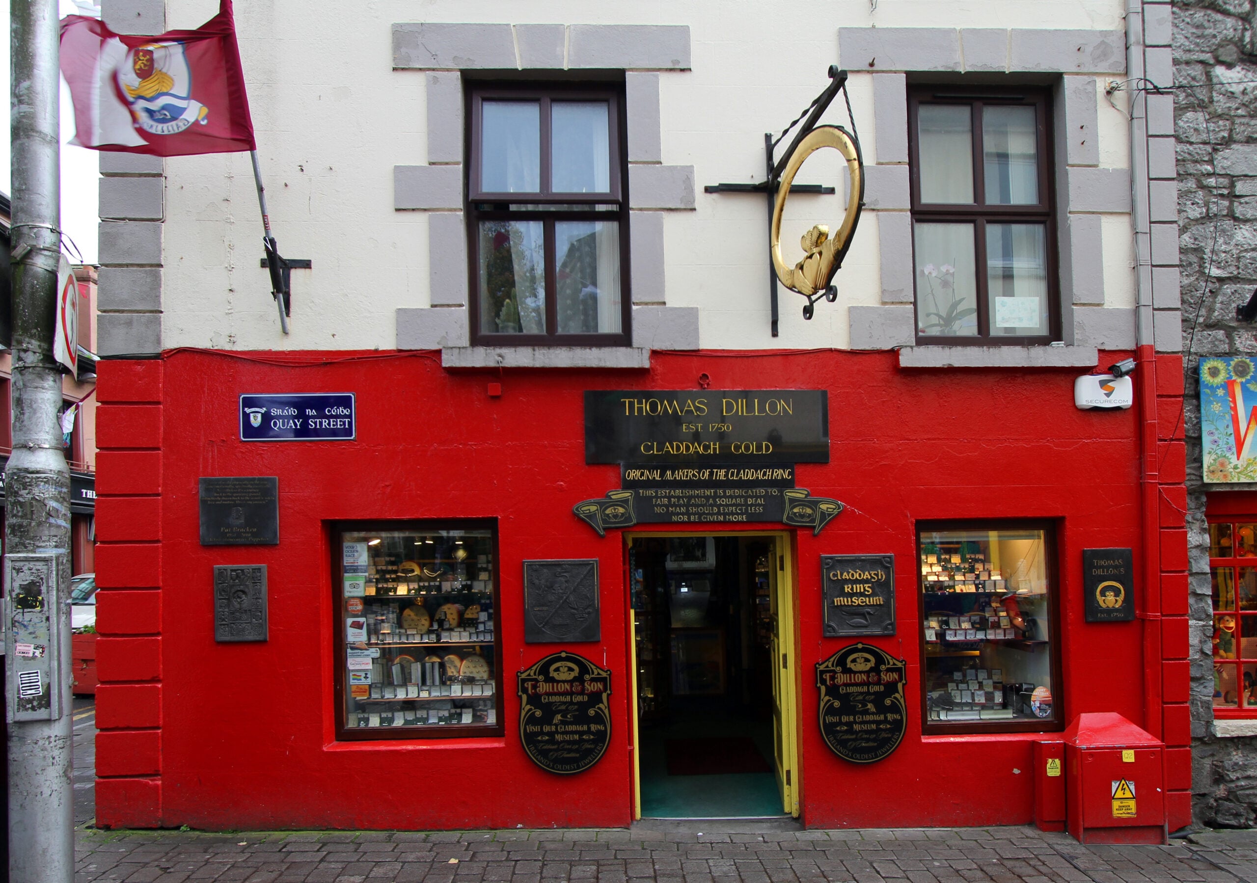 Thomas Dillon's Claddagh Gold jewellers on Quay Street, Galway, with a large gold Claddagh ring &mdash; hands holding a crowned heart &mdash; hanging above the shopfront