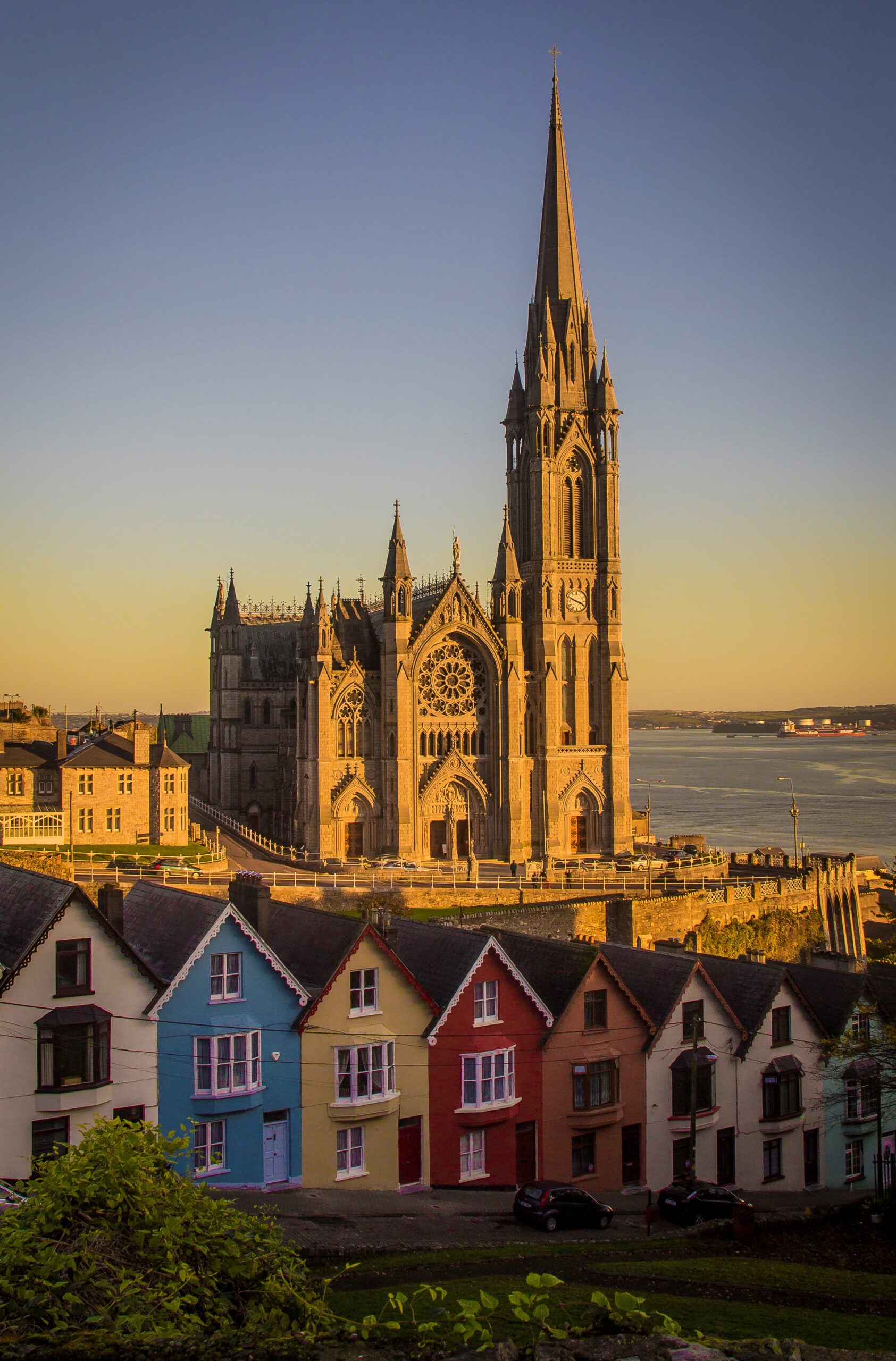 Colourful terraced houses in Cobh, County Cork, with St Colman's Cathedral and Cork Harbour behind