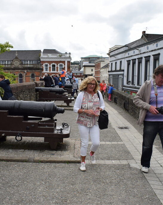 Visitors walking along the historic Derry City Walls past preserved 17th-century cannons overlooking the city