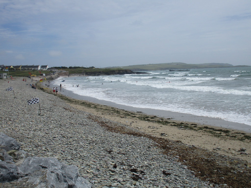 Surfers riding waves at Garretstown Beach, Cork, with safety flags marking the surf zone